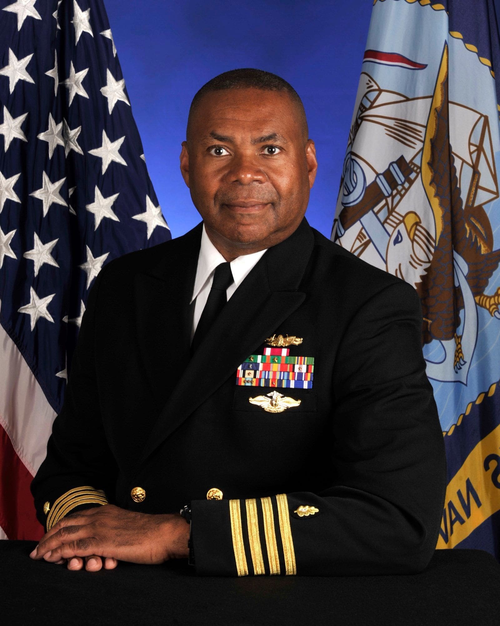 Anthony Boganey U.S. Navy officer in formal uniform with flags.