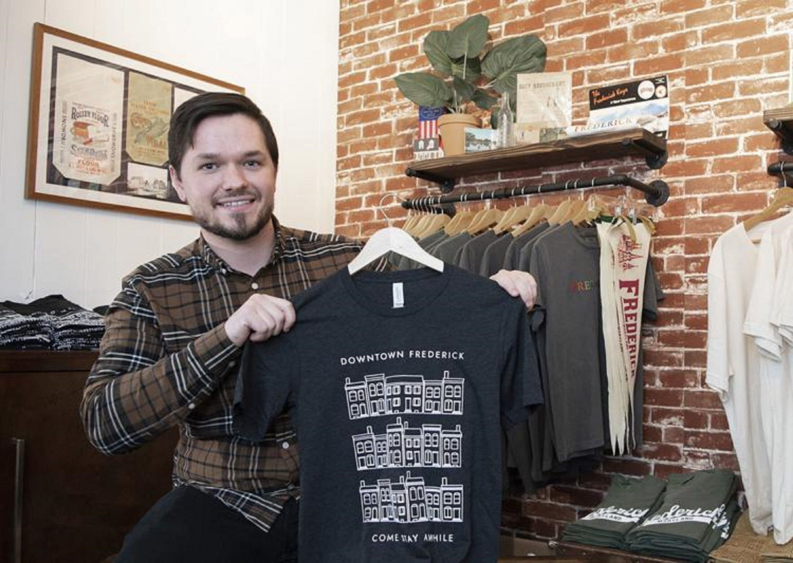 Austin Braswell Man holding Downtown Frederick graphic t-shirt in store.