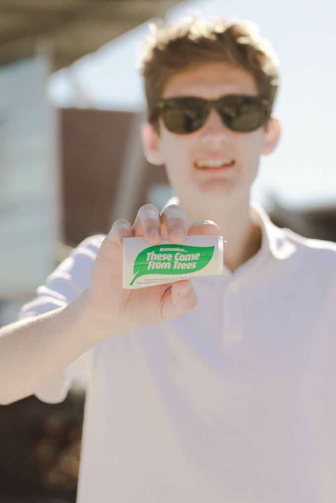 Andrew Nettles Young man holding eco-friendly product package outdoors.