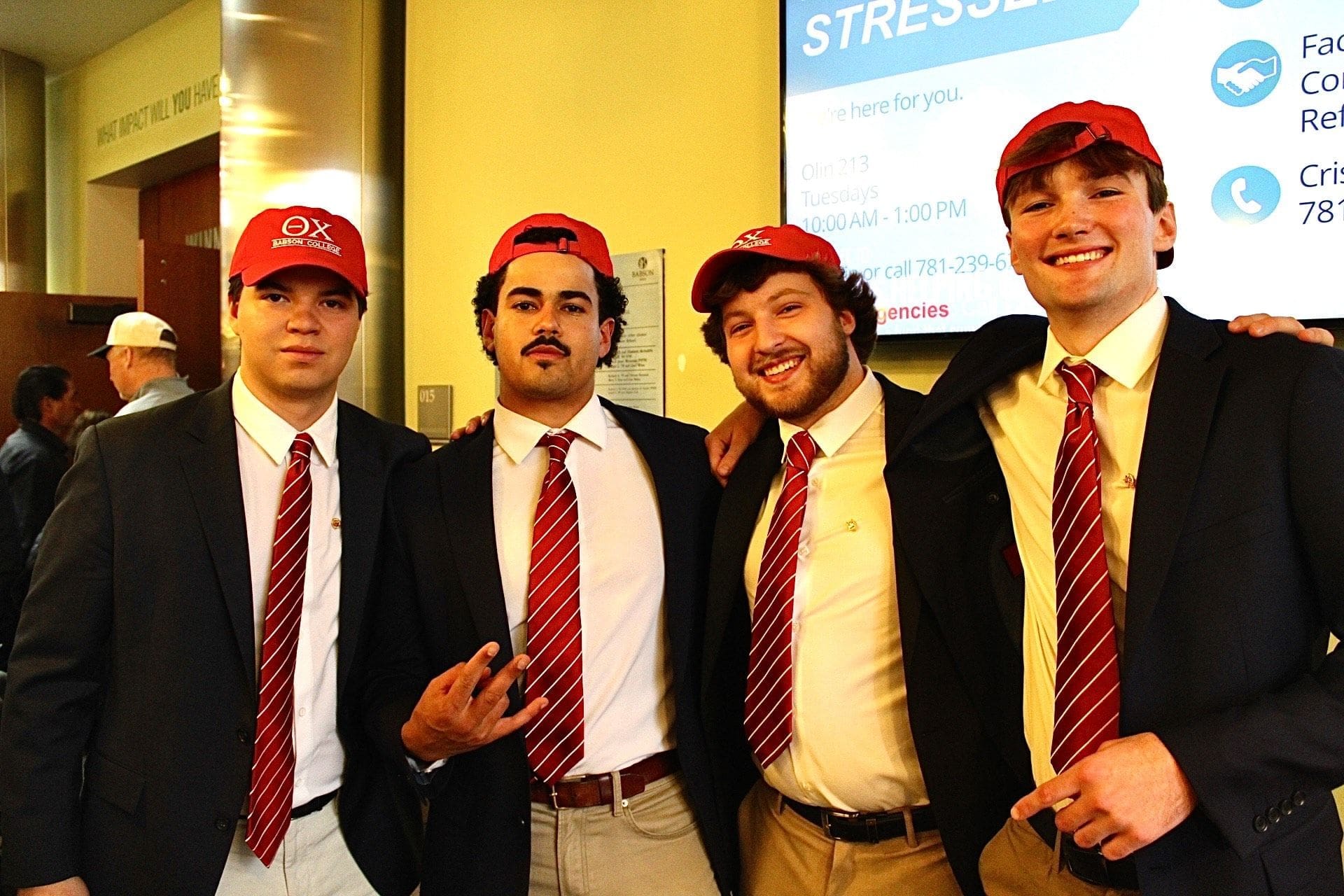 Four men in red hats and ties posing together.