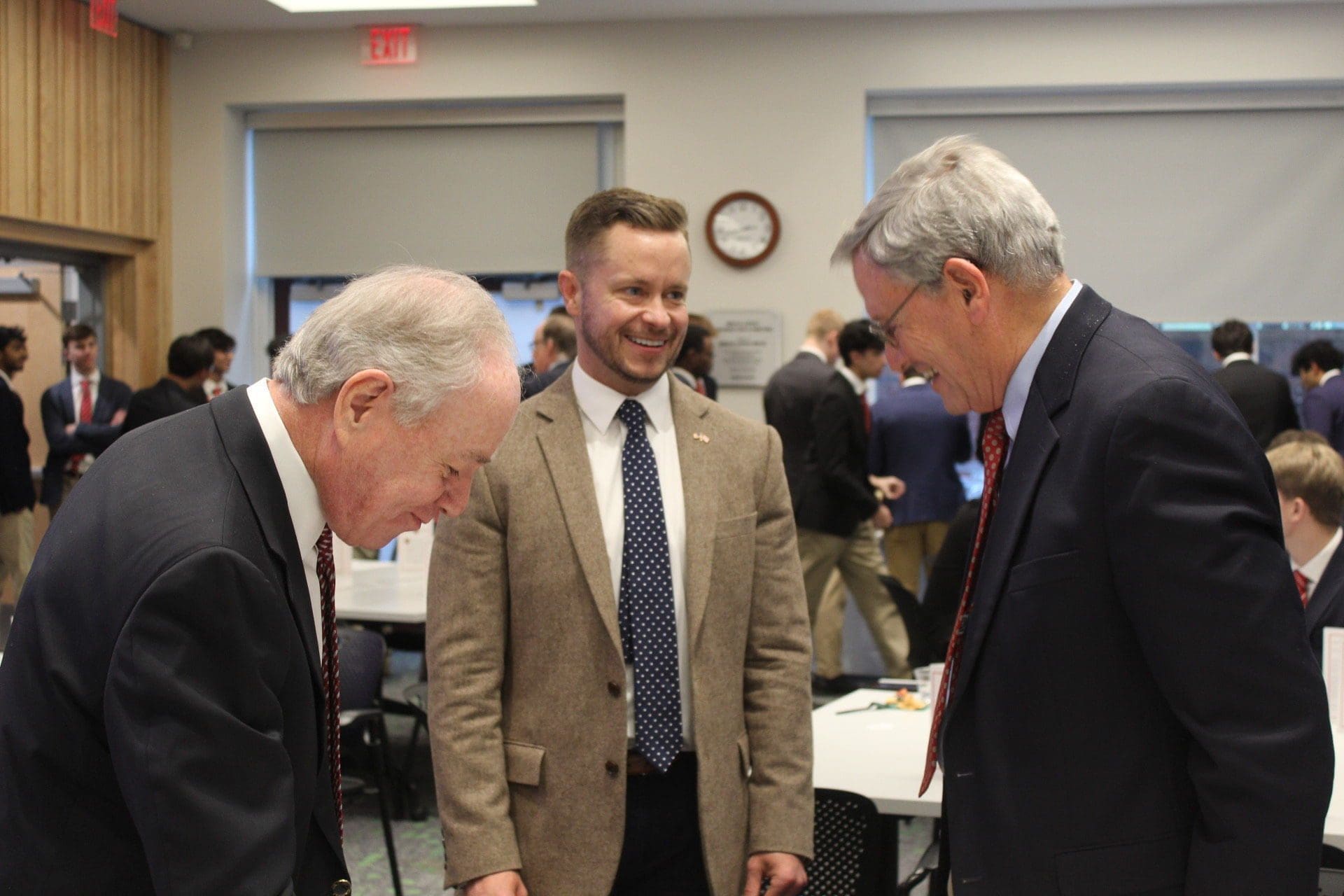 Three men engaged in conversation at a meeting.