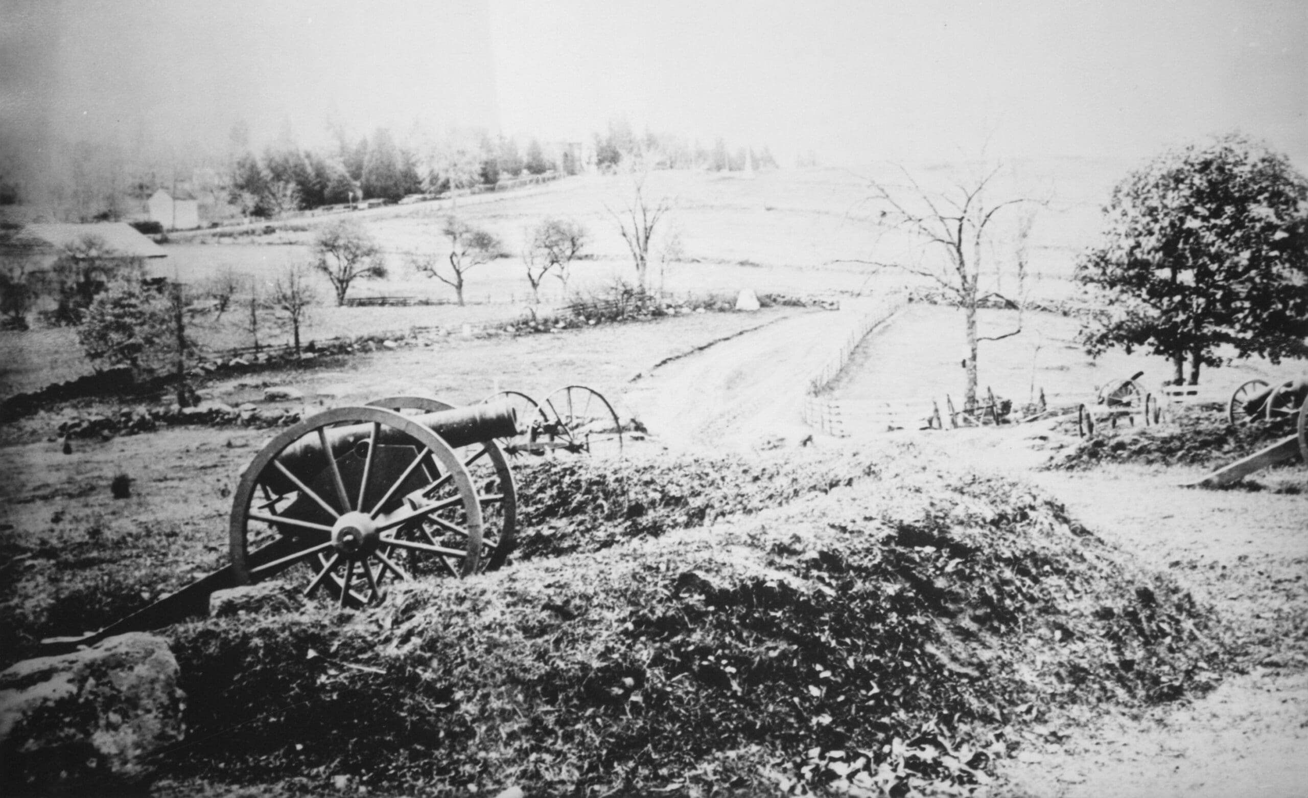 Historic cannon on a battlefield landscape.