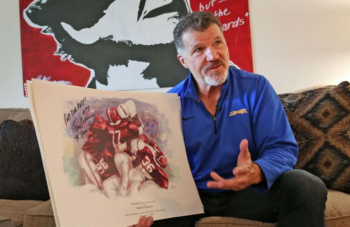 Barry Krauss Man holding signed sports artwork in casual setting.