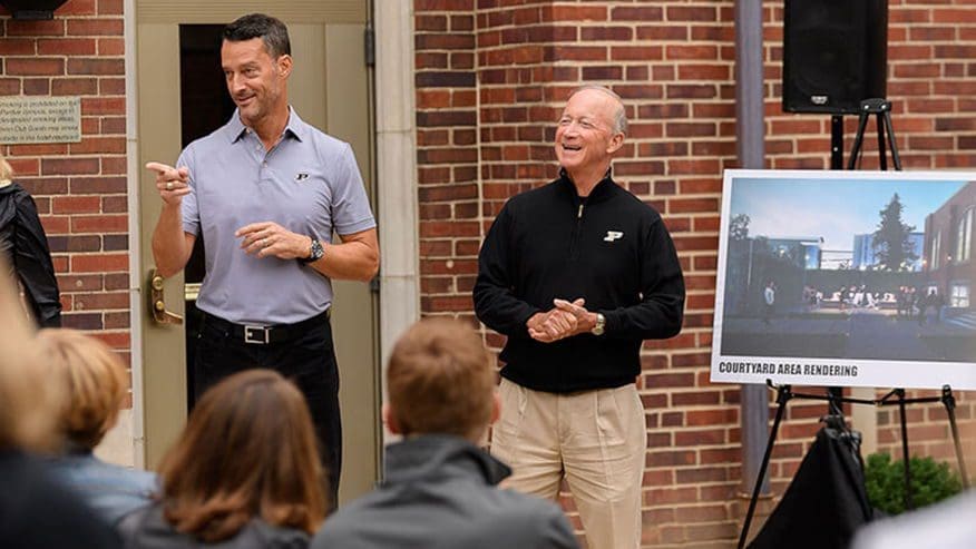 Two speakers presenting at an event, smiling.