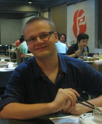 Smiling man dining at a restaurant with chopsticks.