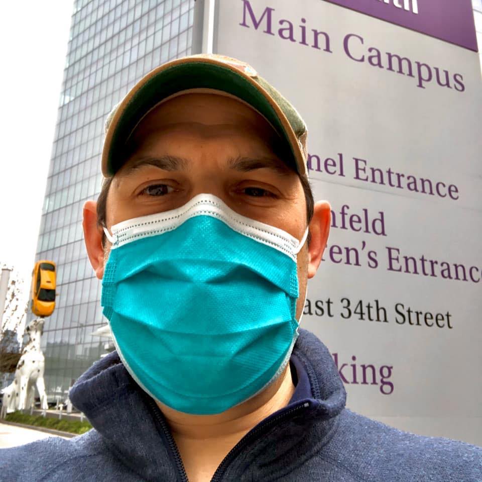 Person wearing mask near campus sign.