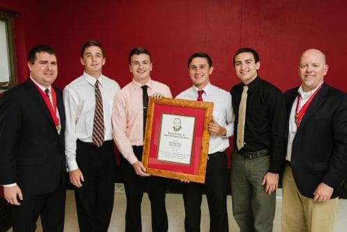 Group of young men holding a framed award.