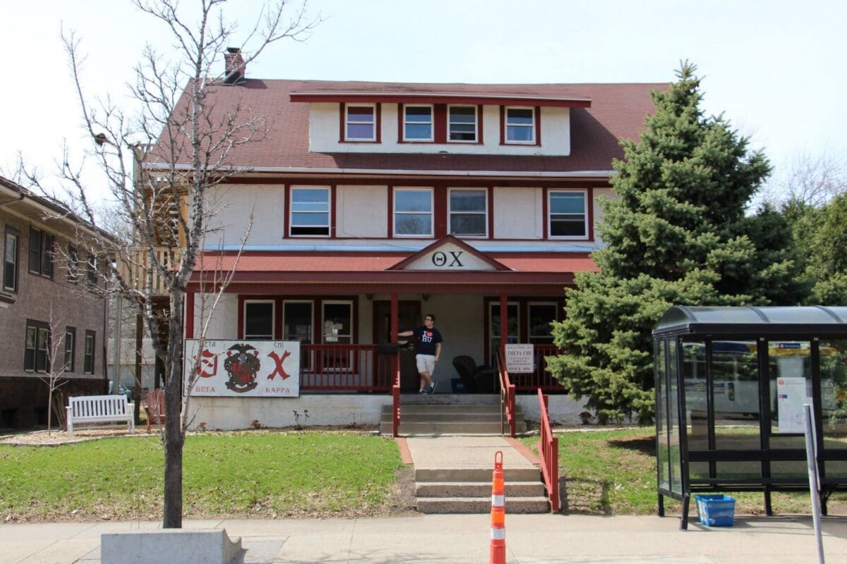 Theta Chi fraternity house with student in front.