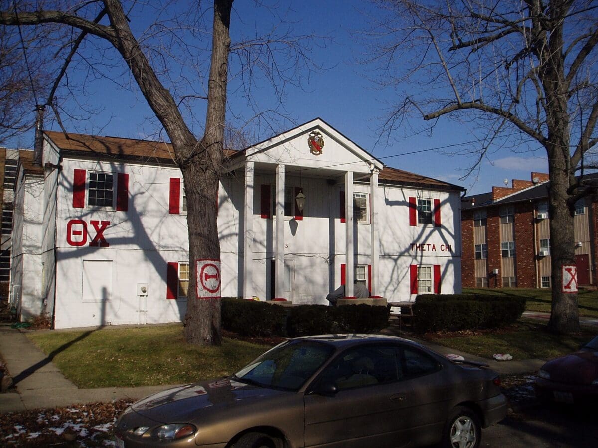 Fraternity house with red shutters and signage.