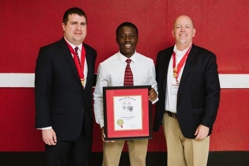 Three men holding an award certificate together.