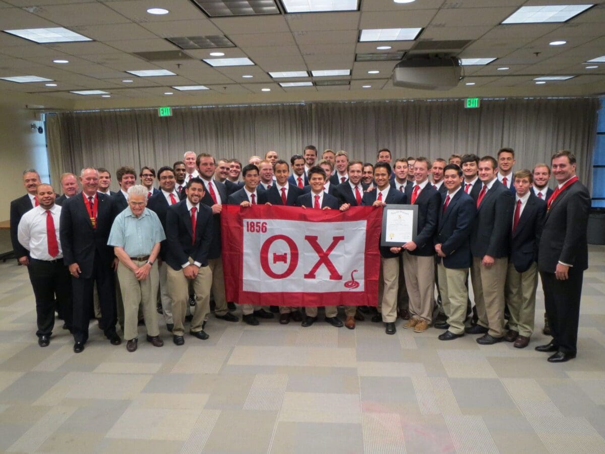 Group photo of fraternity members holding flag.