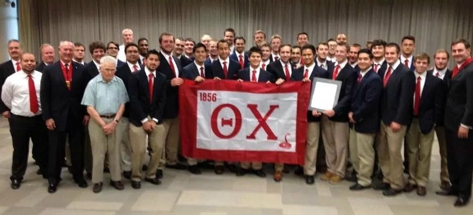 Group photo of fraternity members holding a flag.