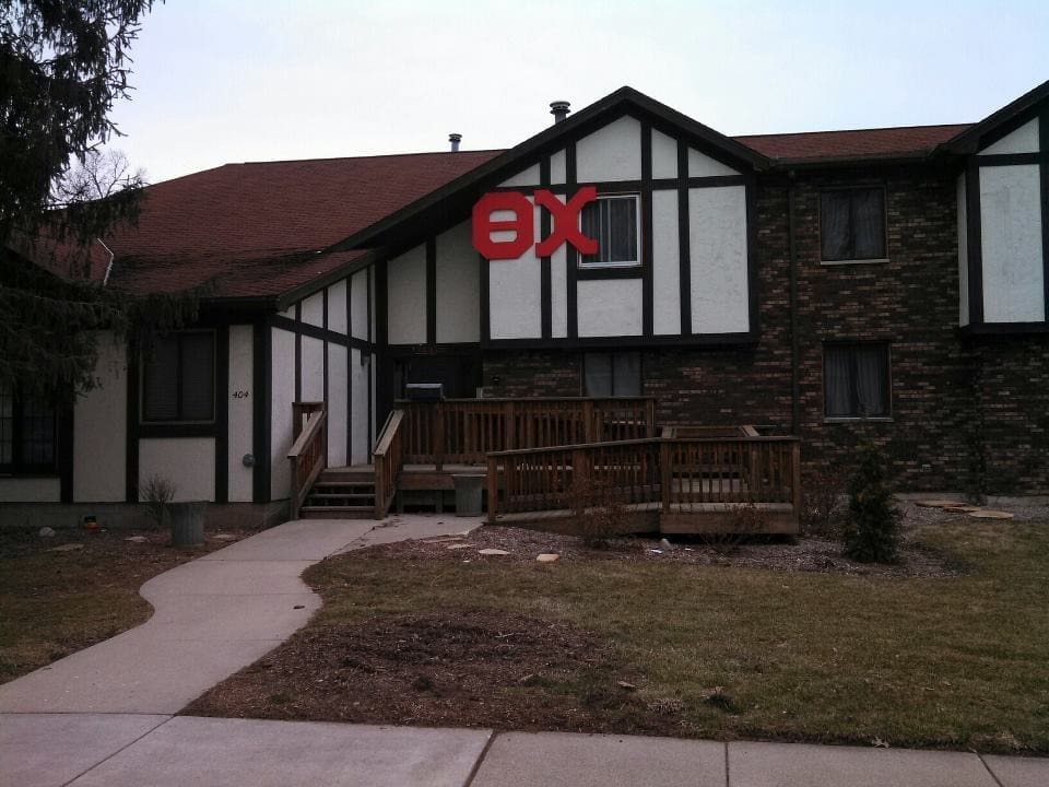 Tudor-style building with wooden porch and landscaping.