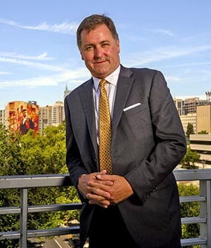 Bill Palmer Businessman in suit with city skyline backdrop.