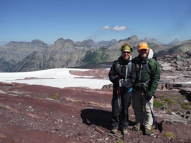 Hikers on a mountain trail with snow-capped peaks.