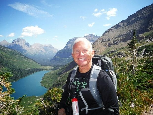 Smiling hiker in scenic mountain landscape with lake.