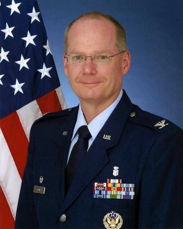 U.S. Air Force officer portrait with flag background.