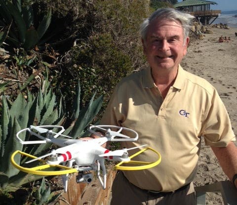 Man holding a drone on the beach.