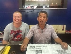 Two men sitting at a table with newspapers.