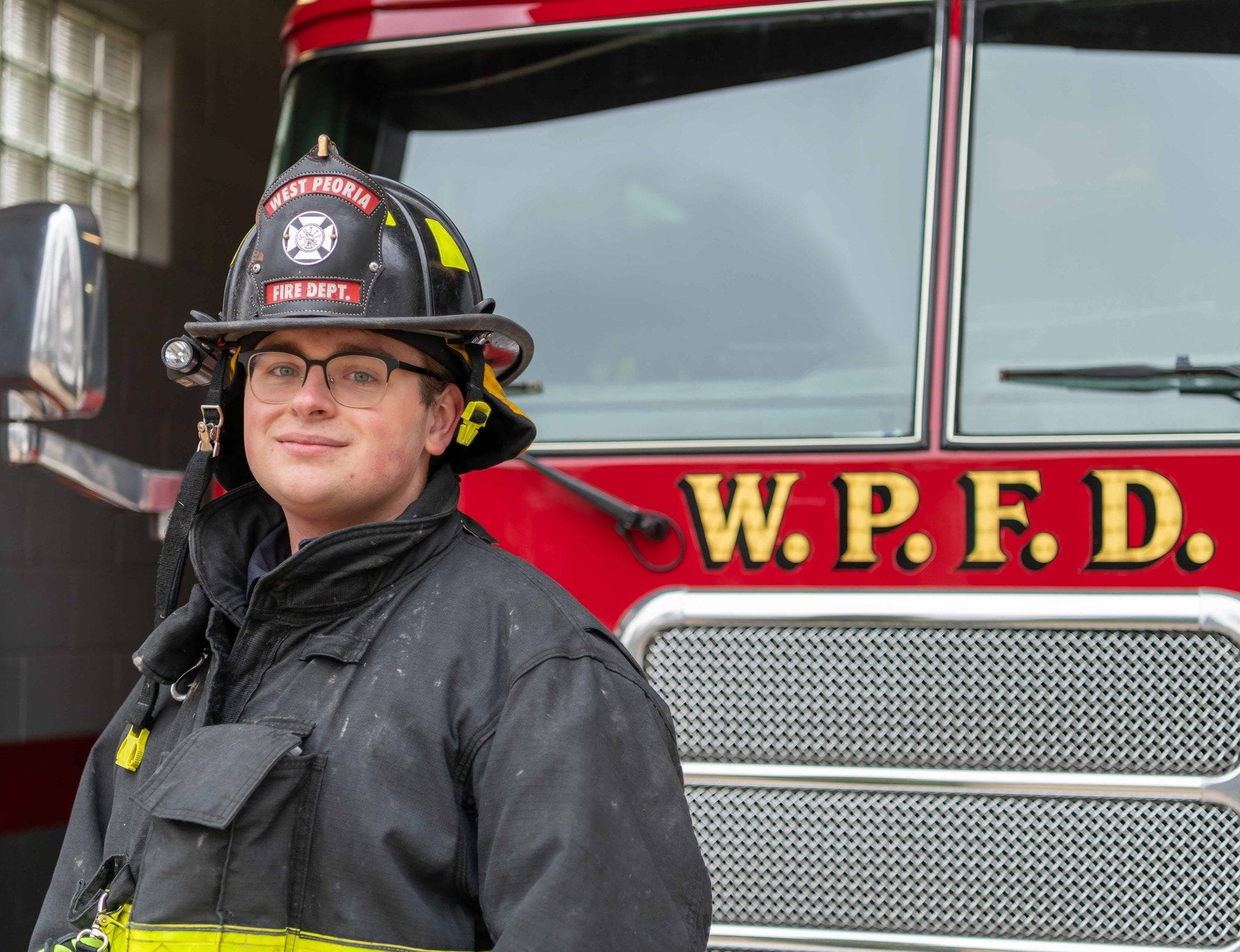 Aaron Coulombe - Bradley Firefighter in uniform near fire truck.