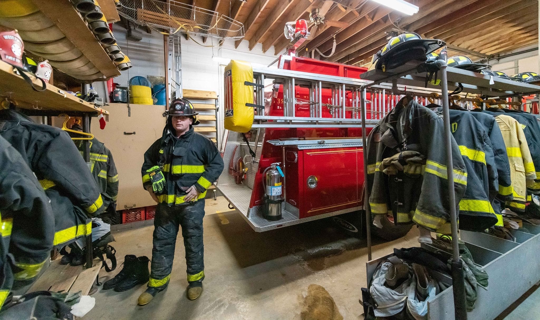 Aaron Coulombe - Bradley Firefighter standing beside a fire truck in garage.