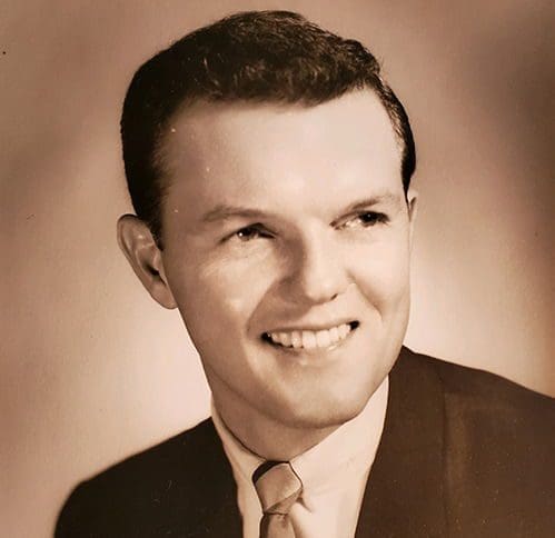 Smiling man in vintage black and white portrait.
