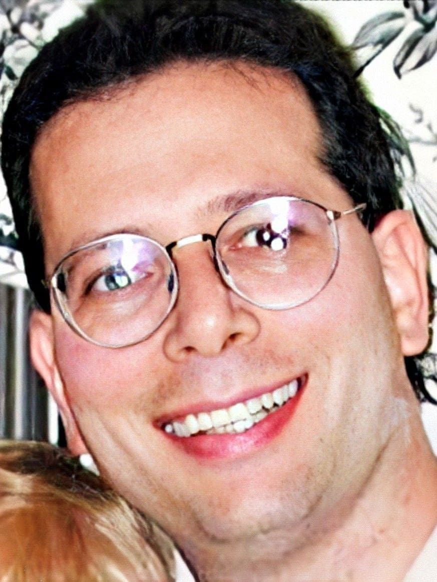 Smiling man with glasses and light brown hair.