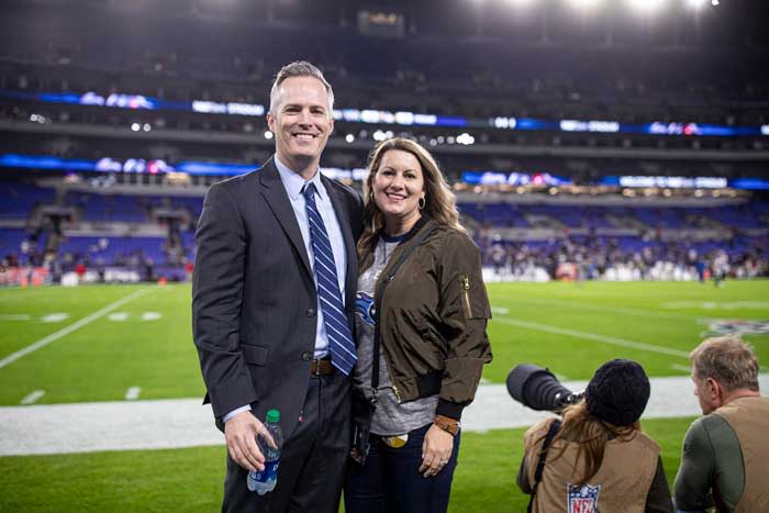 Couple smiling on football field during game.