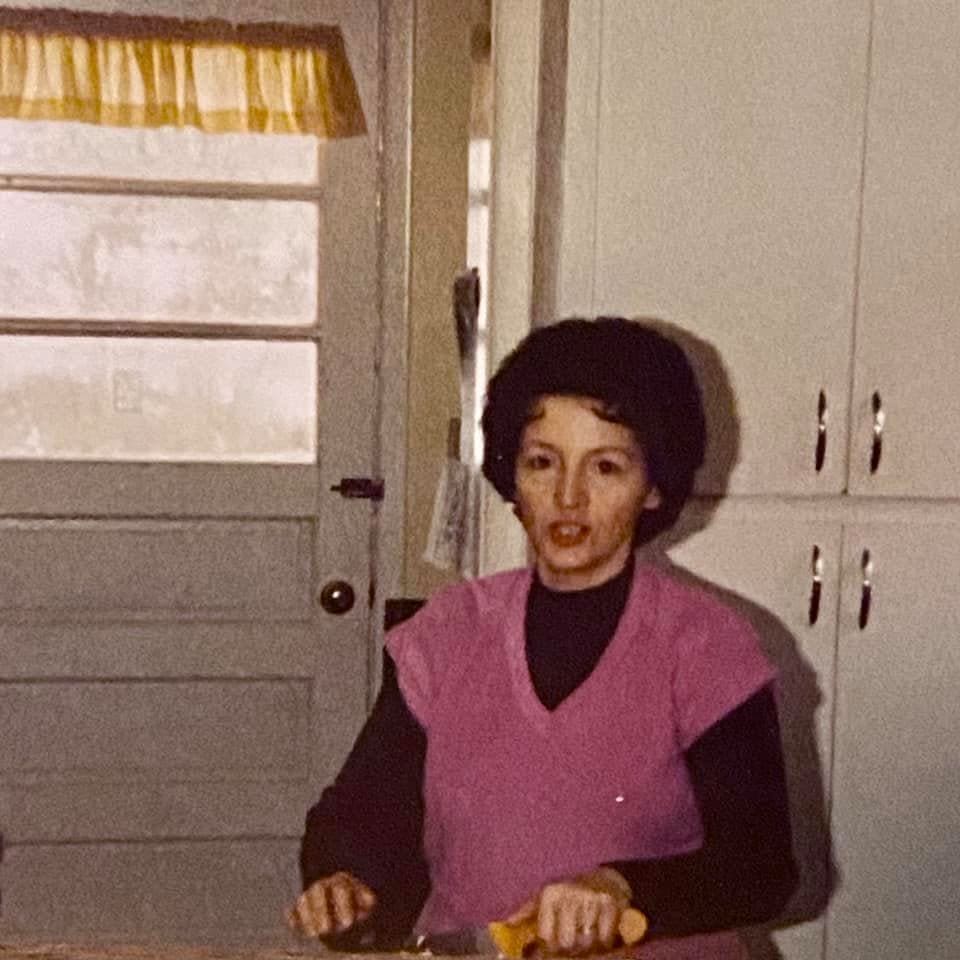 Woman cooking in a vintage kitchen setting.