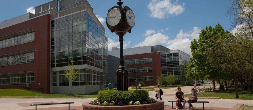 Historic clock tower in campus courtyard with greenery.