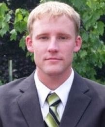 Young man in suit with green tie outdoors.