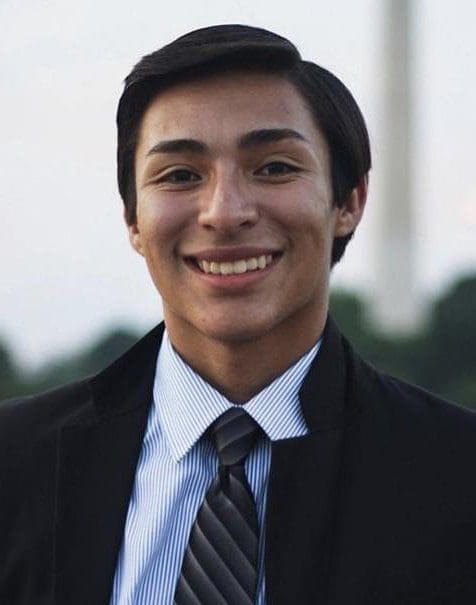 Smiling young man in a formal suit outdoors.