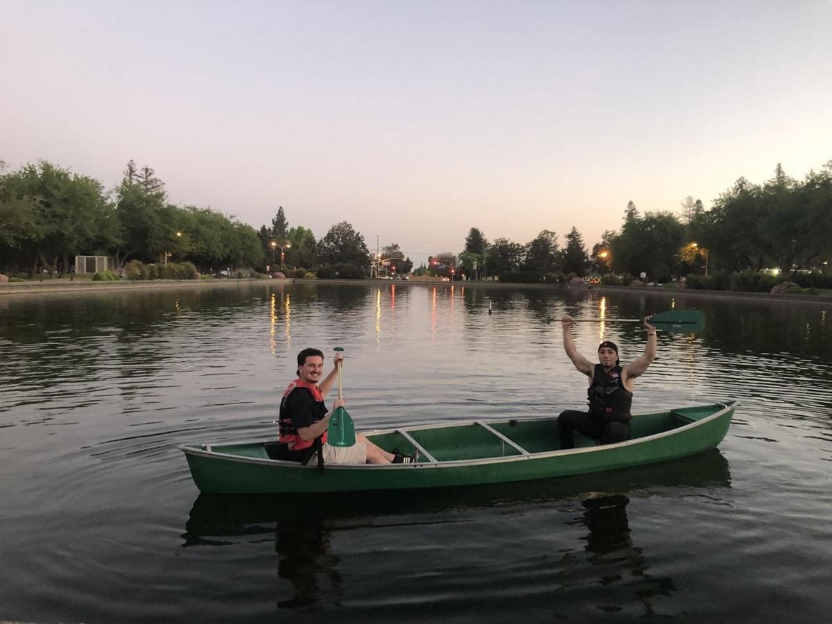 Two friends canoeing on a calm lake at sunset.