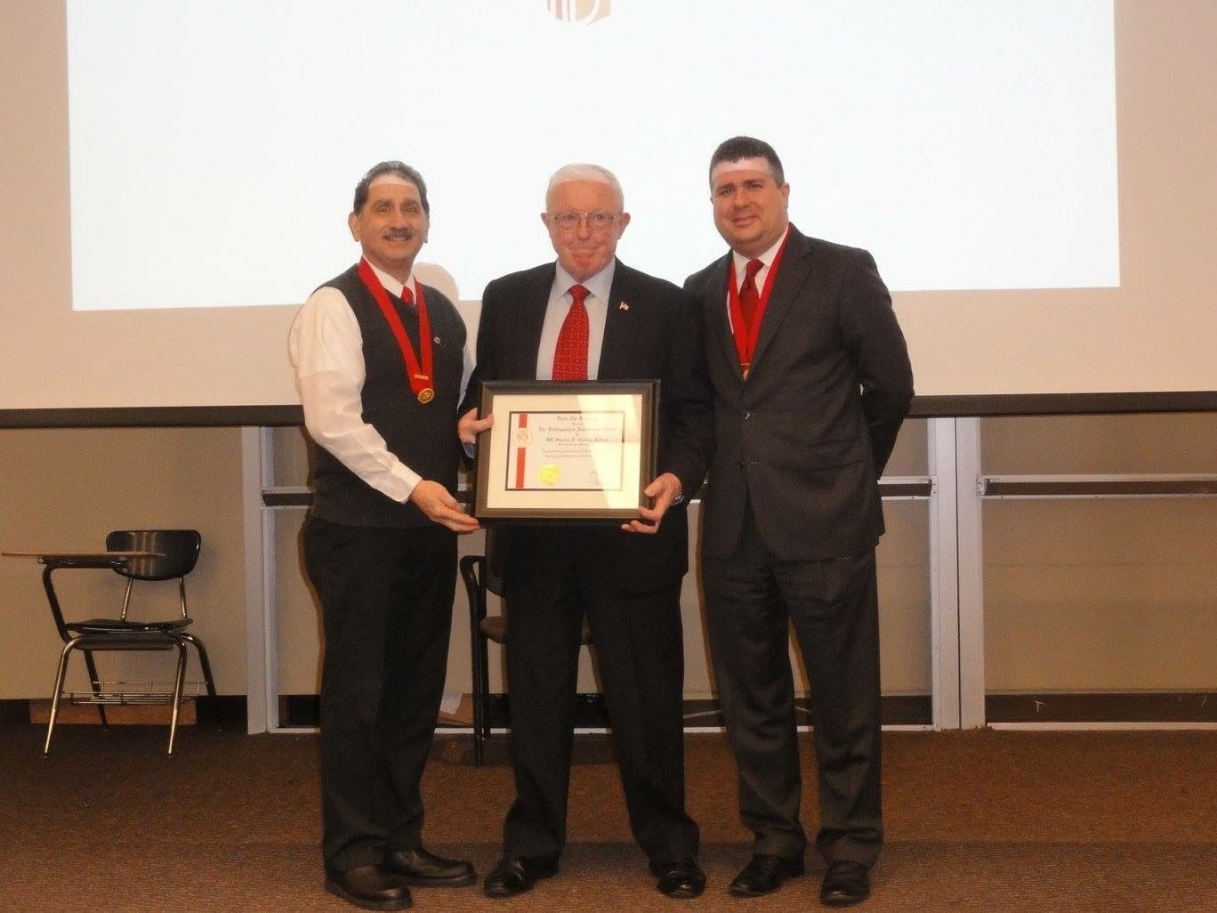 Three men holding an award certificate at an event.