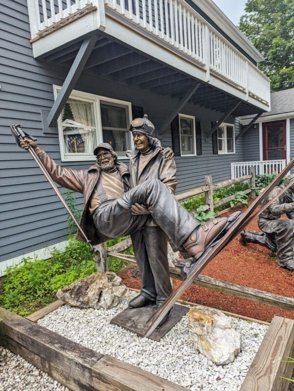 Bronze statue of skiers celebrating together outdoors.