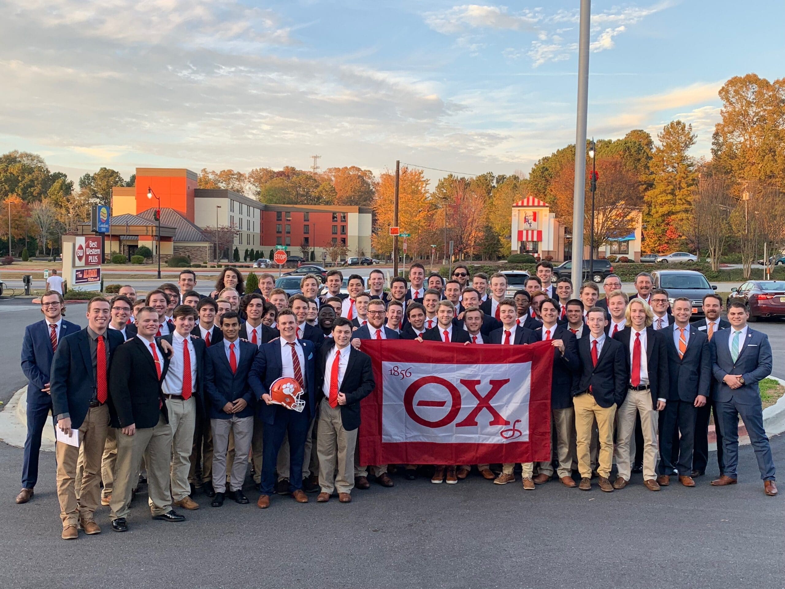 Group of fraternity members holding a flag outdoors.