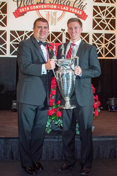 Two men holding a trophy at an awards ceremony.