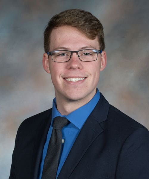 Young man in professional attire smiling for portrait.