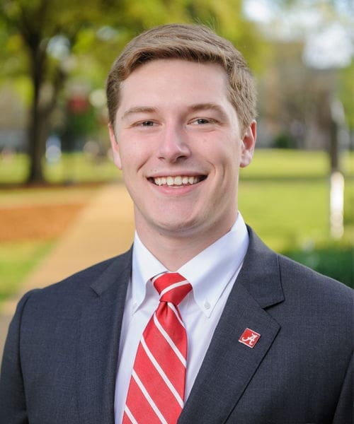 Smiling young man in a suit outdoors.