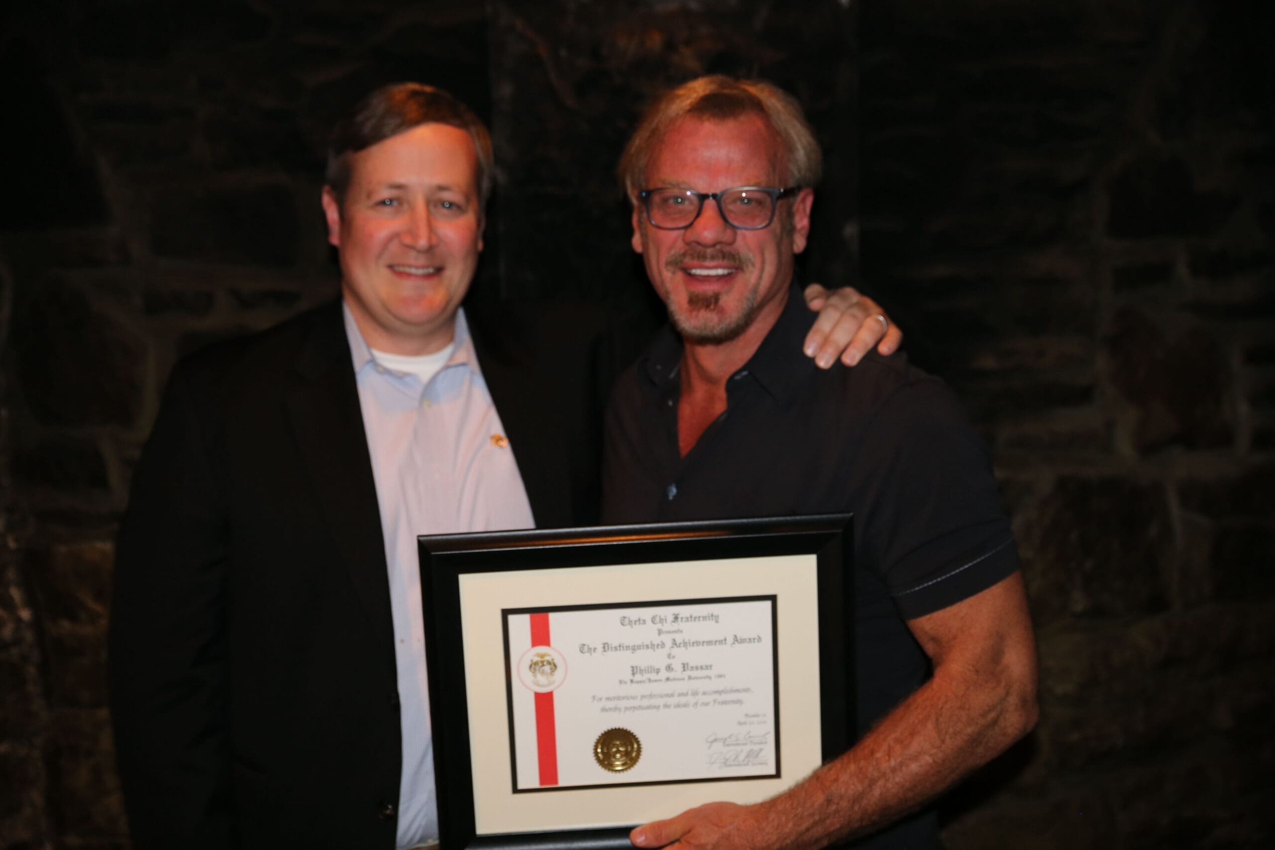 Two men proudly holding a framed certificate.