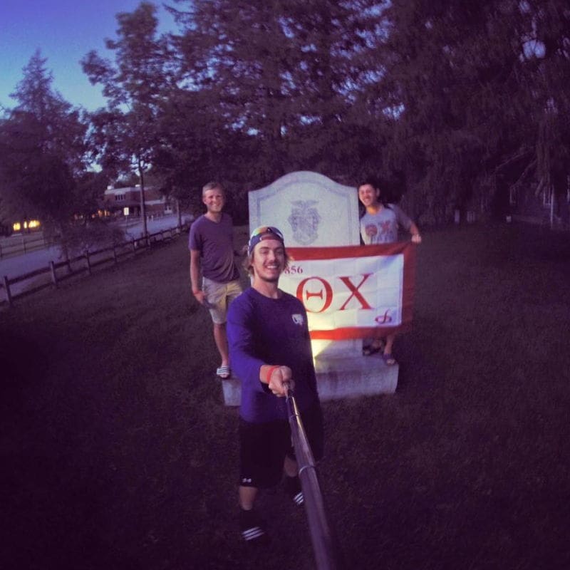 Friends posing in front of a fraternity sign.