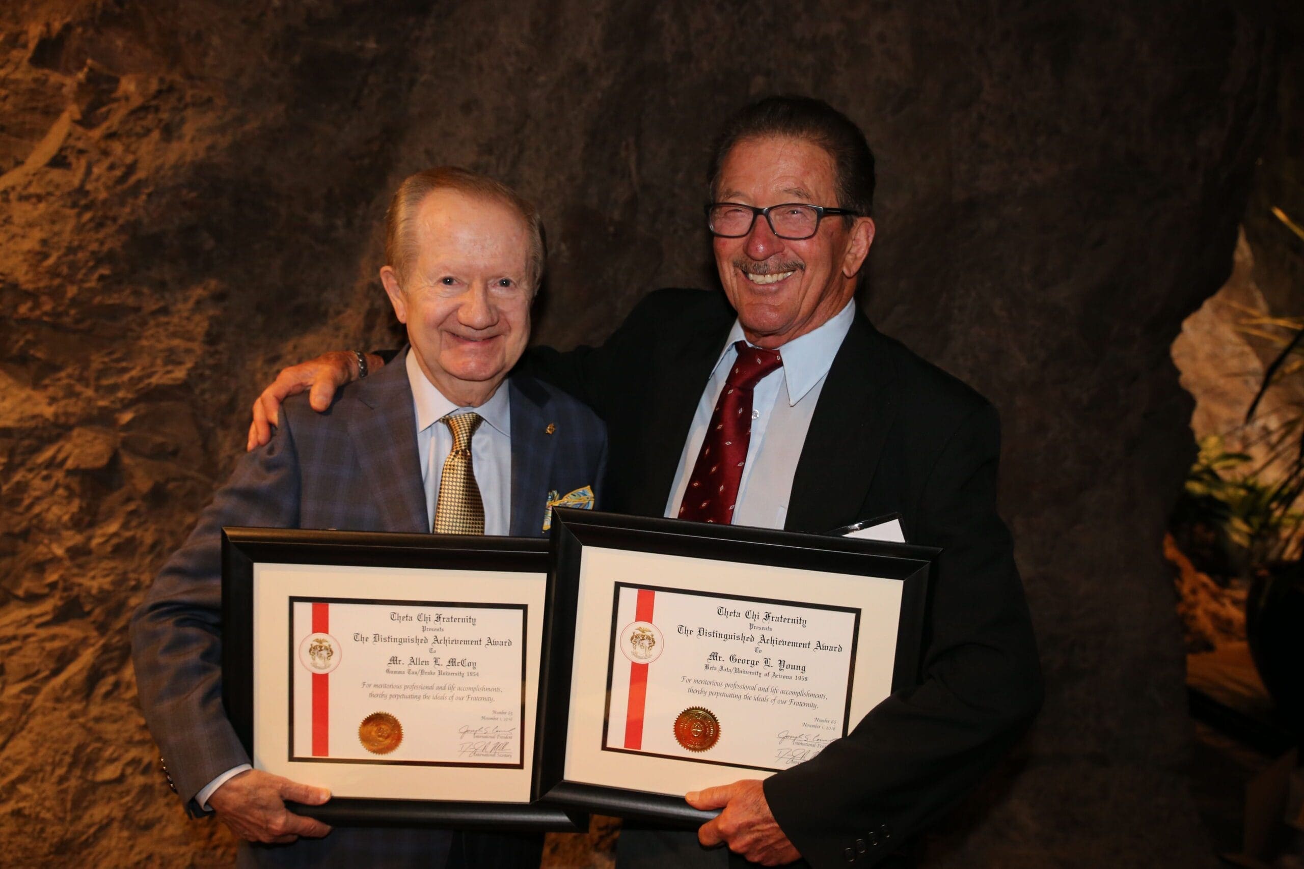 Two men proudly holding framed certificates.
