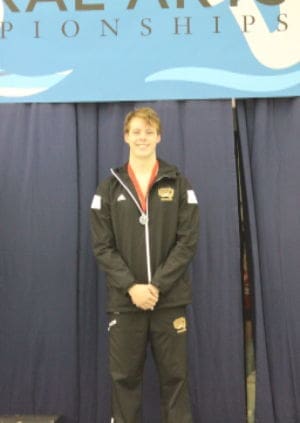 Swimmer in medalist attire at competition event.