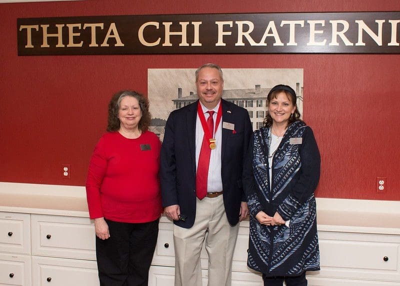 Three individuals posing at Theta Chi Fraternity event.