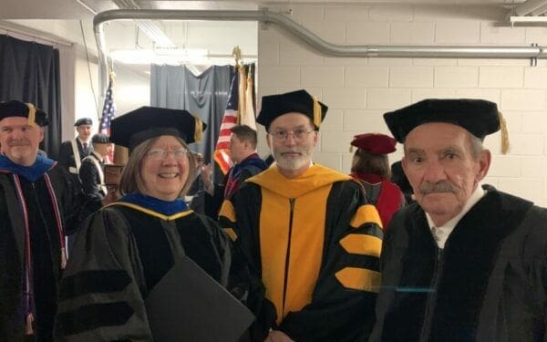 Dean DuCray Academic ceremony with graduates in traditional regalia.