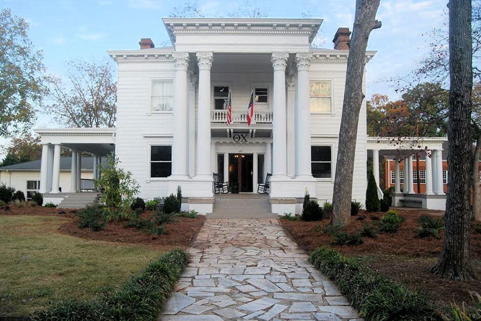 Historic white mansion with columns and landscaped pathway.