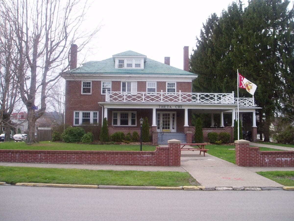 Historic brick house with green roof and porch.