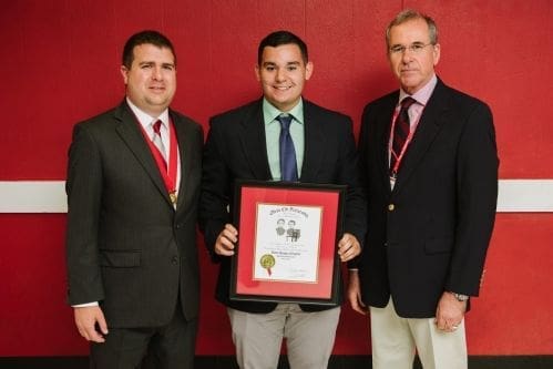 Three men holding an award certificate together.