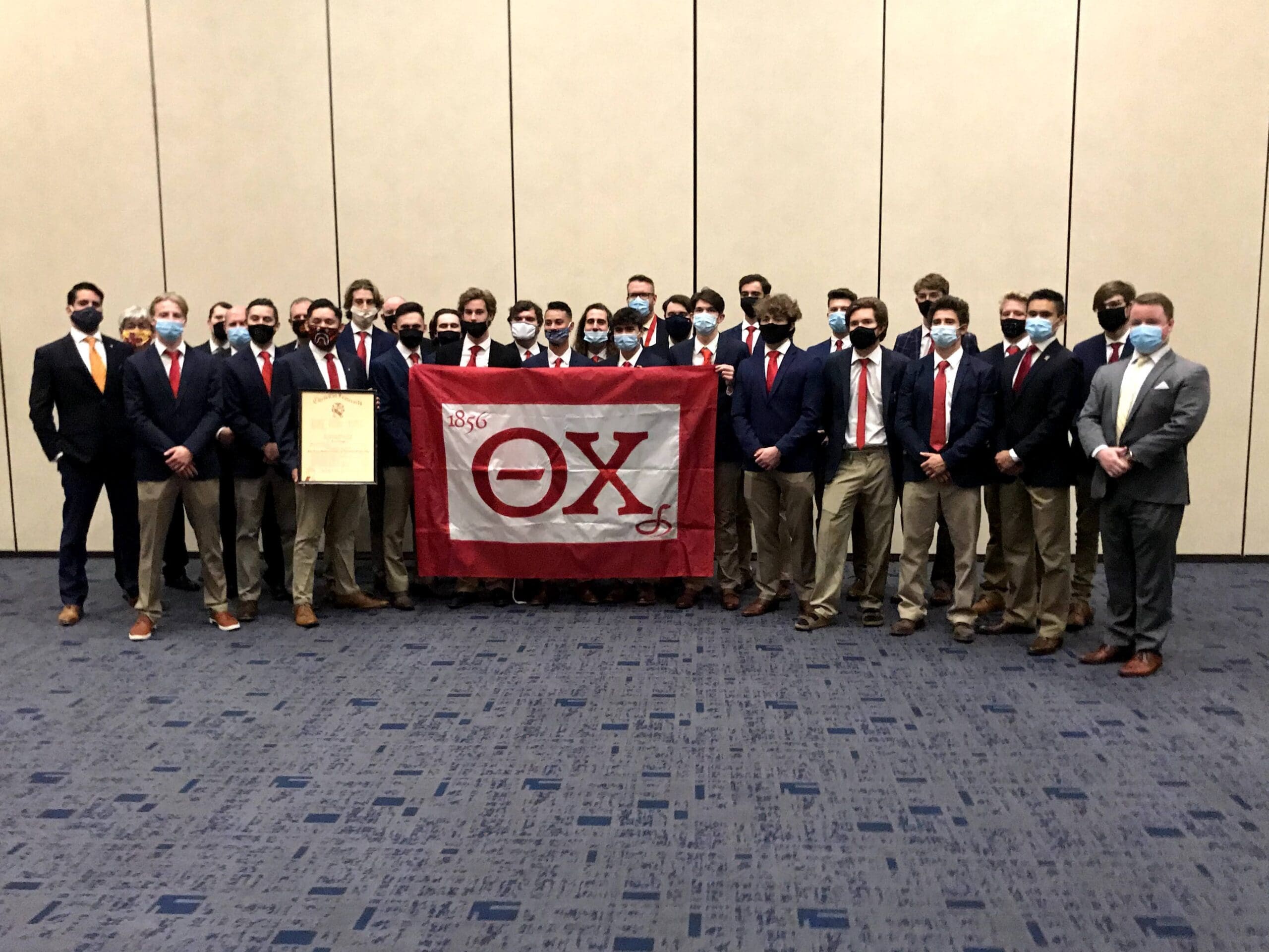 Delta Upsilon - Arizona State Group of fraternity members posing with a flag.