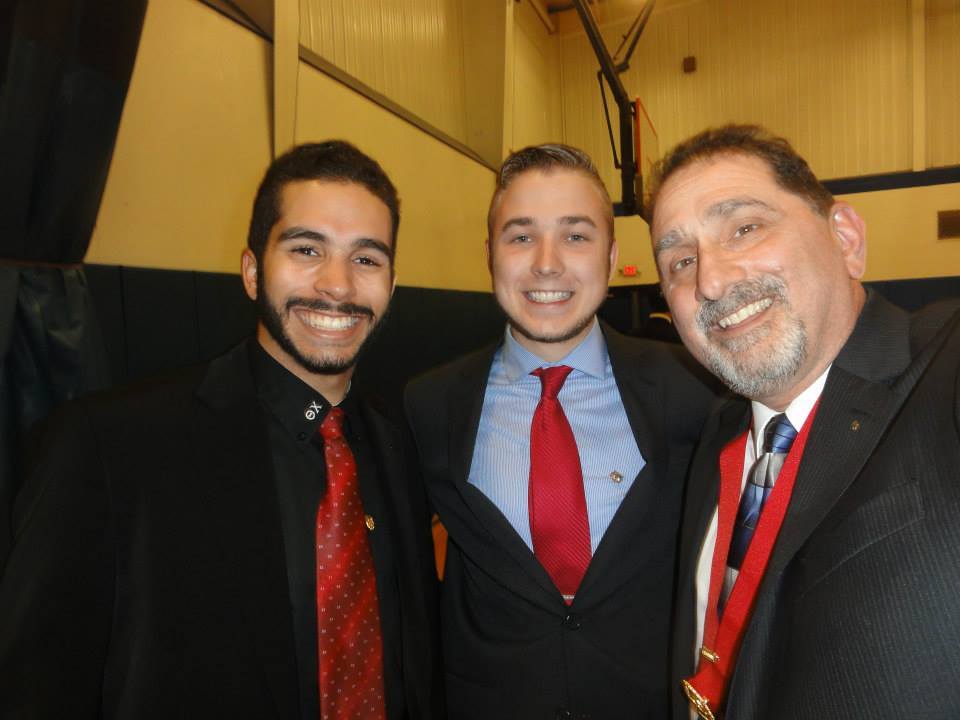 Three men smiling together at a formal event.